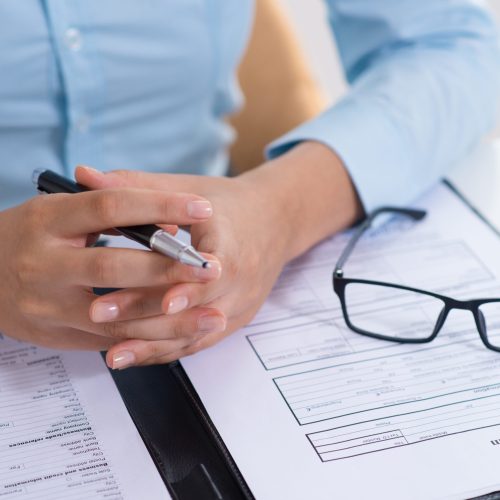 Closeup of boss reading filled application form. Business person sitting at desk. Recruitment concept. Cropped front view.